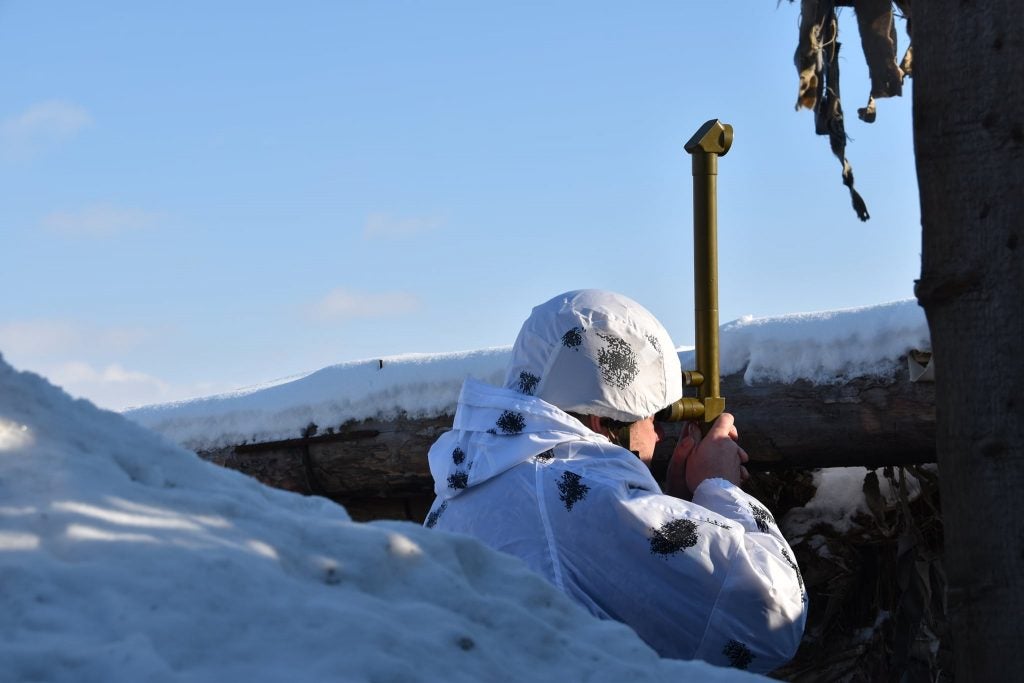 An Ukrainian soldier of the 30th Mechanized Brigade uses a periscope to surveil the surroundings of their defensive position. (30th Mechanized Brigade)